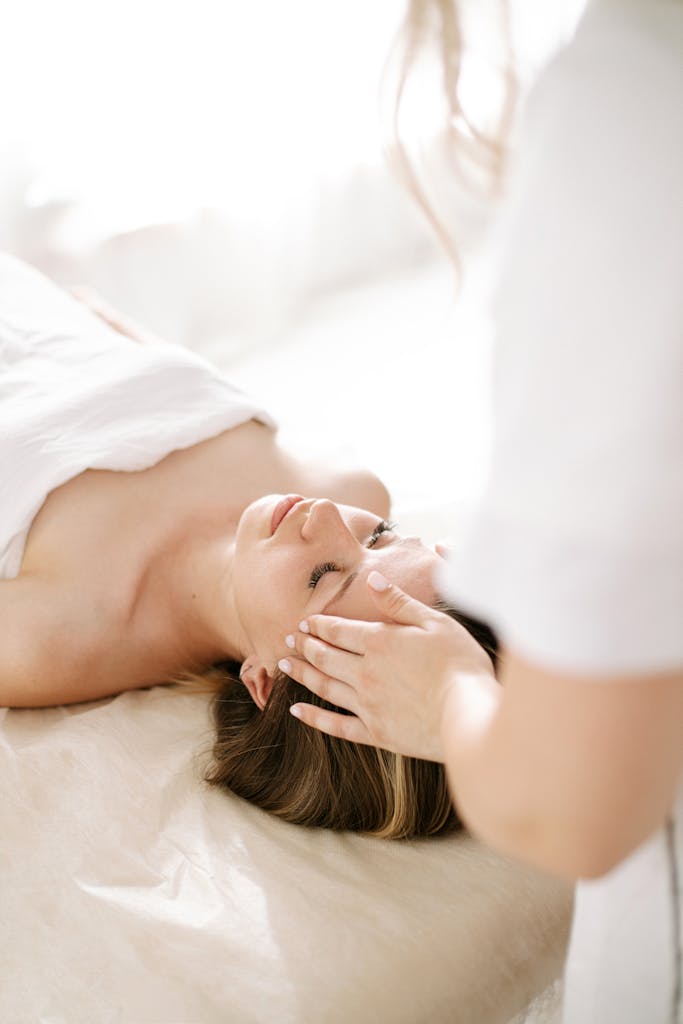 Woman enjoying a calming head massage at a spa, promoting relaxation.